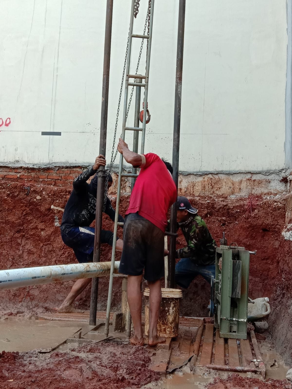 Tim pengeboran sumur bor bekerja di lokasi proyek bangunan dengan tanah merah