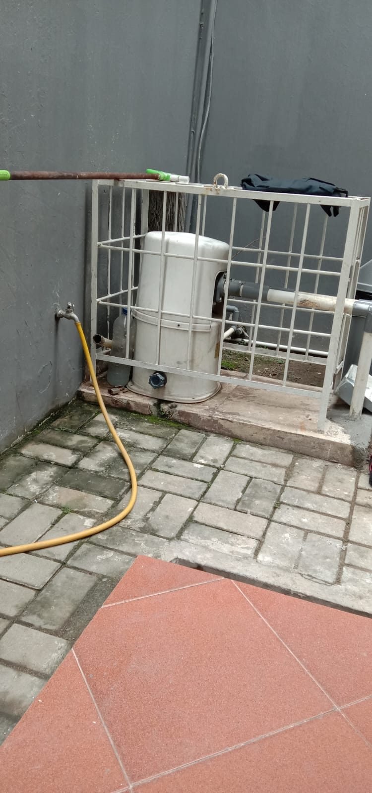 Pompa air terpasang di dalam kandang besi pengaman di area taman rumah